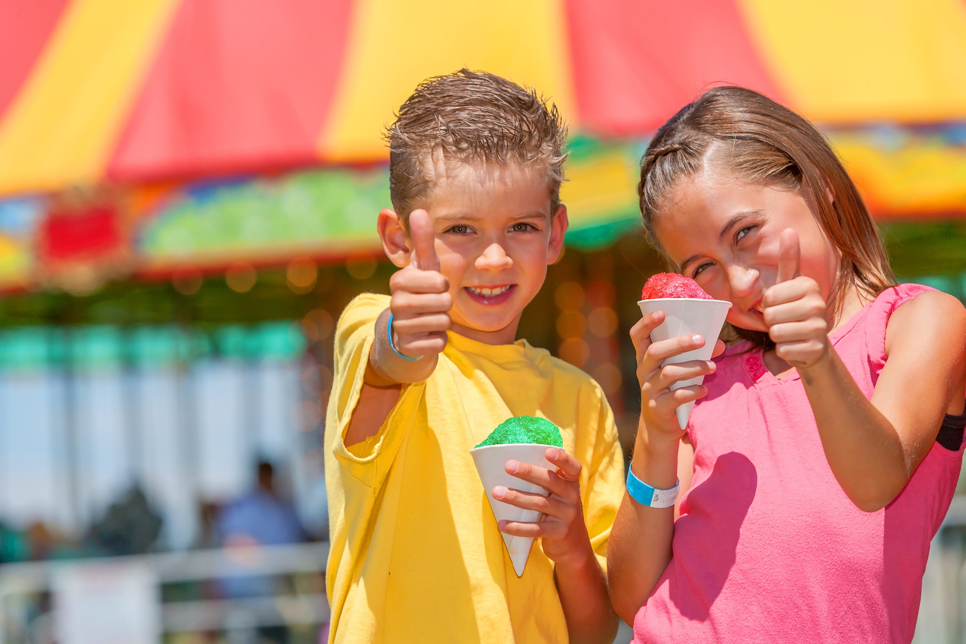 Two kids giving thumbs up with colourful snow cones