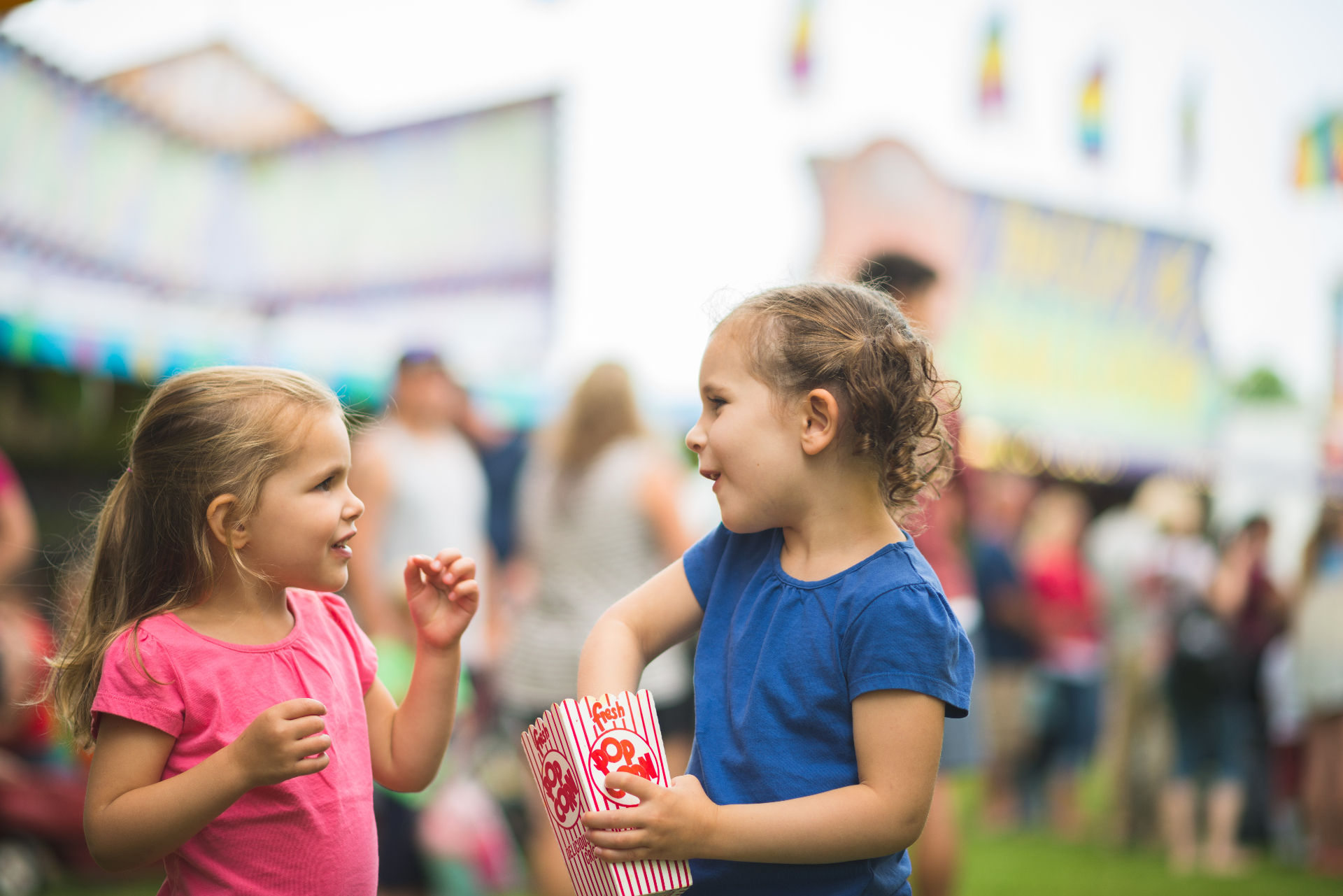 Two girls sharing popcorn at the fair