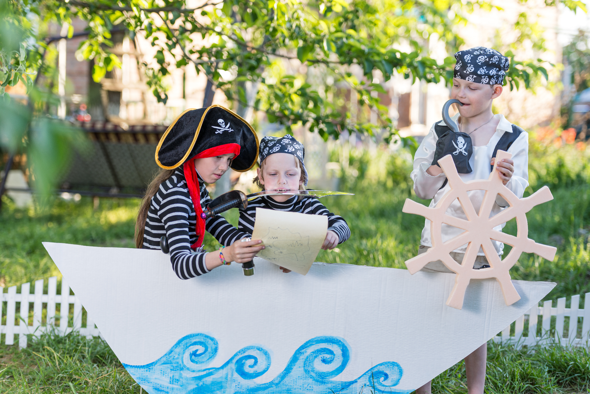 Kids in pirate costumes on a cardboard ship with treasure map