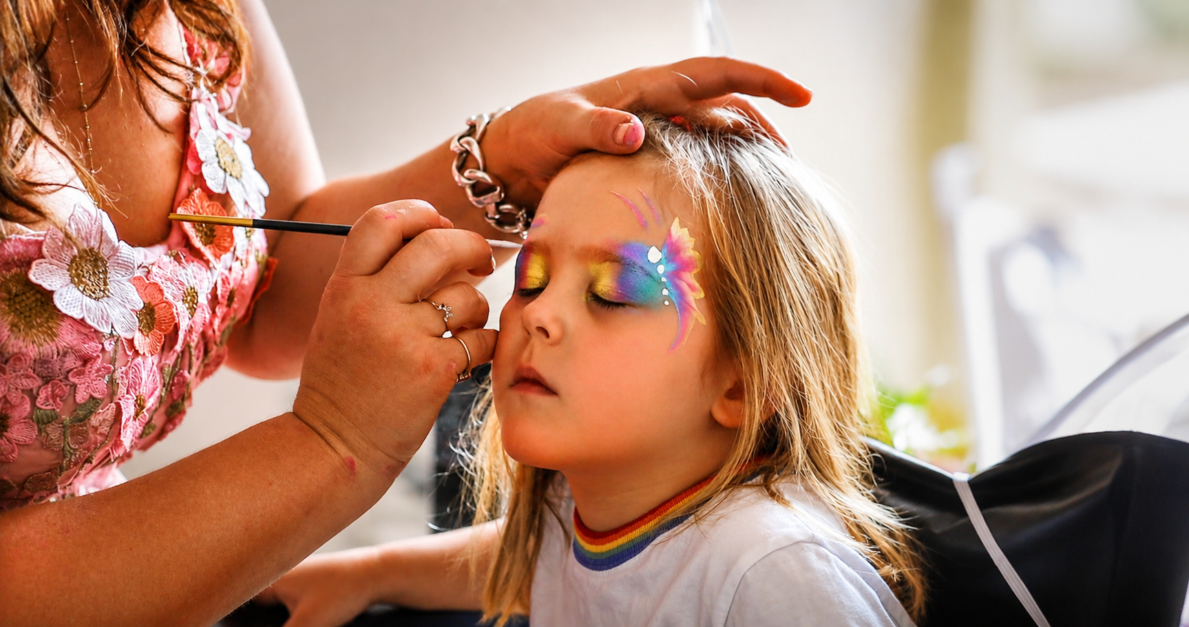 Child having a rainbow butterfly painted on her face